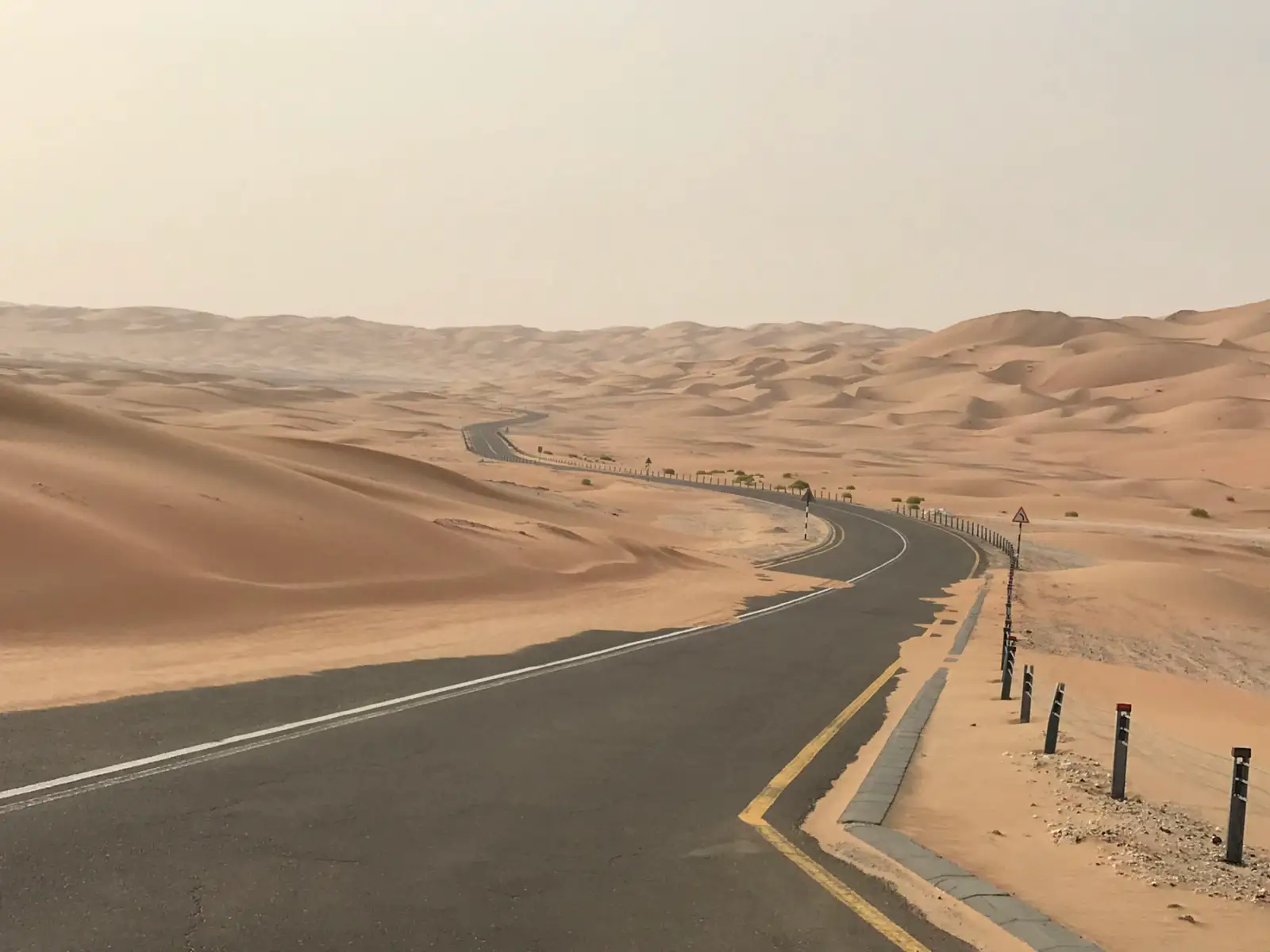 A road curving through desert dunes